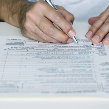 Man Filling out Tax Form --- Image by © Royalty-Free/Corbis